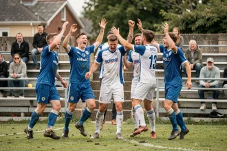 Joueurs de football amateur du District Aisne célébrant un but lors d'un match du week-end sur un terrain régional